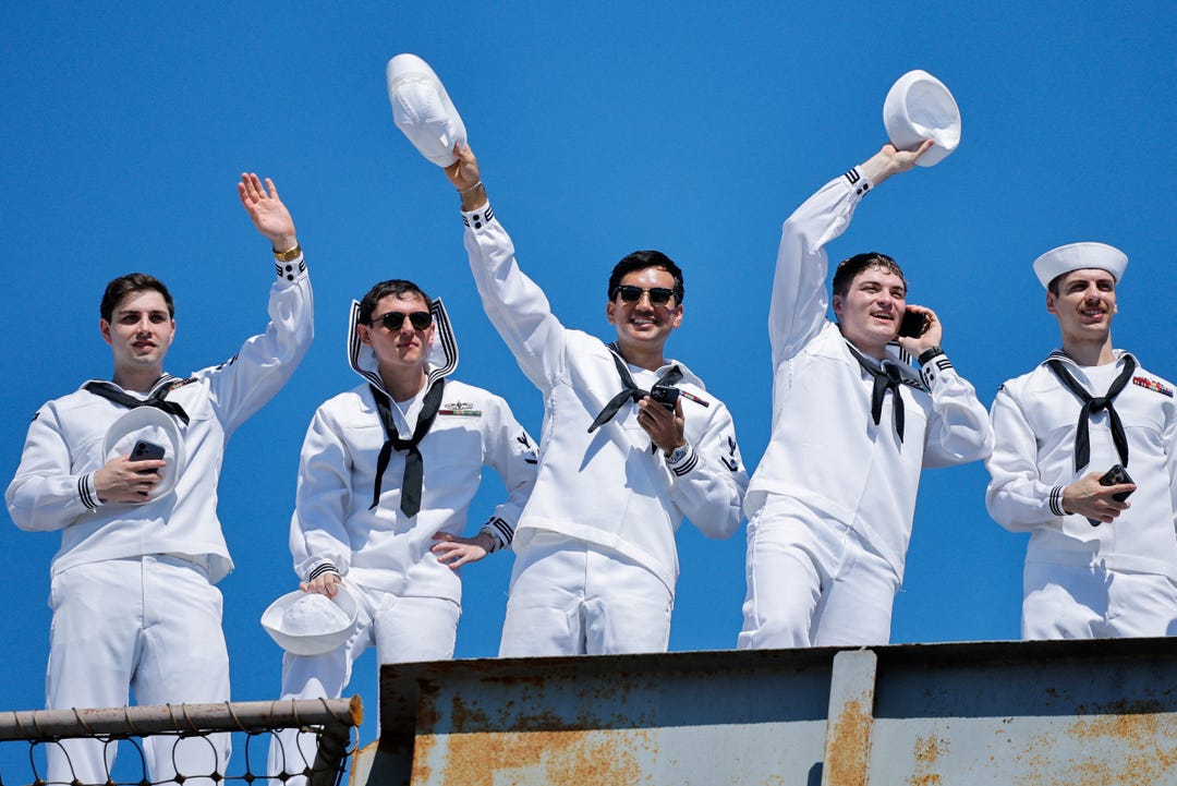 Sailors wave their hats from the US Navy Nimitz-class aircraft carrier USS Abraham Lincoln as it returns home following an extended deployment in the Middle East at Naval Base Coronado in San Diego, California, on Oct. 8, 2026.