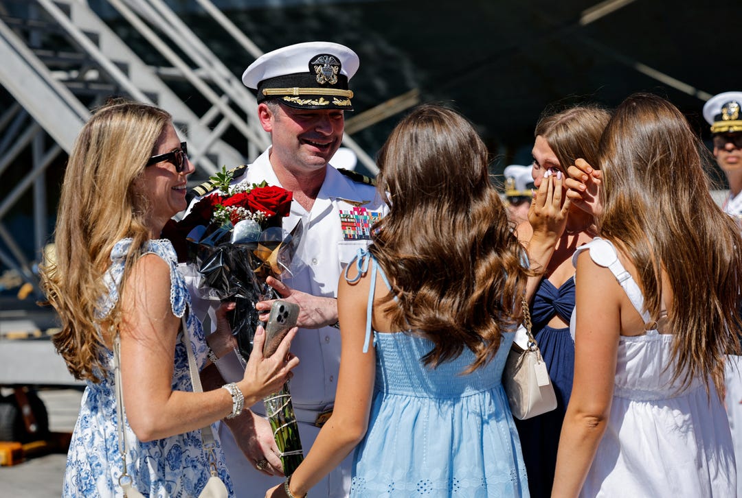 Captain Dan Keeler, USS Abraham Lincoln's commanding officer greets his family members after the US Navy Nimitz-class aircraft carrier USS Abraham Lincoln returned home following an extended deployment in the Middle East at Naval Base Coronado in San Diego, California, on Oct. 8, 2026.