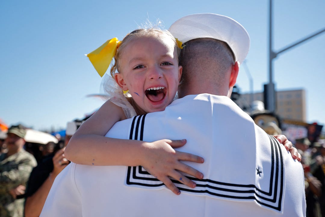 Sailor Timothy Nickles greets his daughter after the US Navy Nimitz-class aircraft carrier USS Abraham Lincoln returned home following an extended deployment in the Middle East at Naval Base Coronado in San Diego, California, on Oct. 8, 2026.