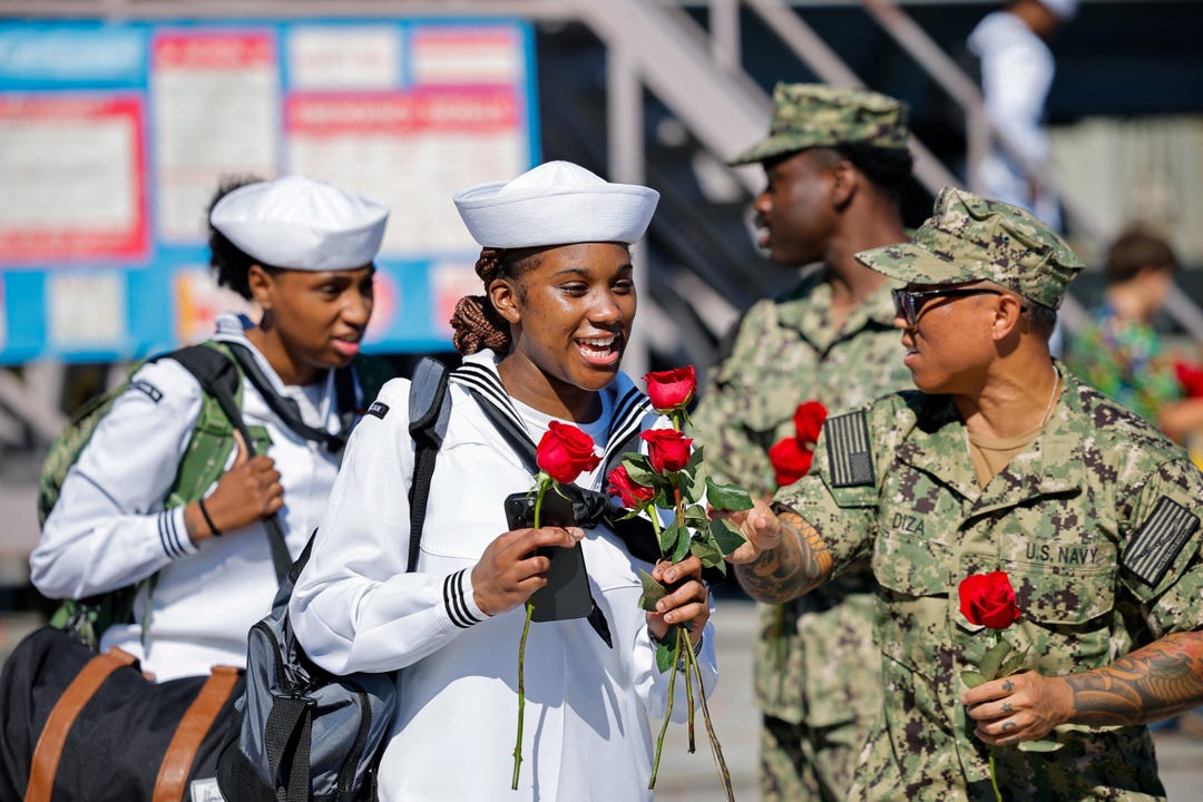 A sailor holds roses after disembarking the Nimitz-class aircraft carrier USS Abraham Lincoln after it returned home following an extended deployment in the Middle East at Naval Base Coronado in San Diego, California, on Oct. 8, 2026.