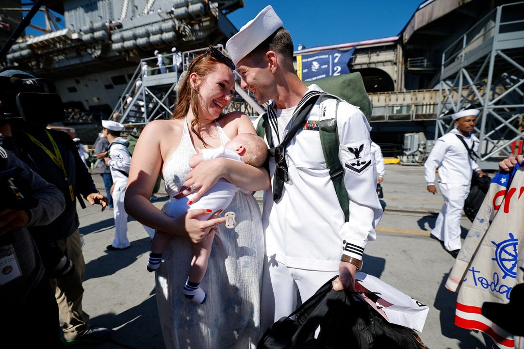 Saylor Caleb Atkins greets his wife McKenzie Atkins, as she holds their baby after the US Navy Nimitz-class aircraft carrier USS Abraham Lincoln returned home following an extended deployment in the Middle East at Naval Base Coronado in San Diego, California, on Oct. 8, 2026.