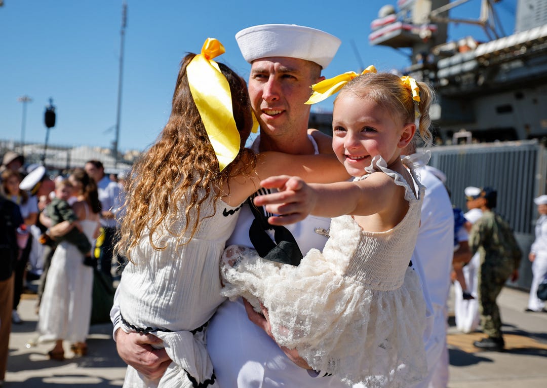 Sailor Timothy Nickles greets his daughters after the USS Abraham Lincoln returned from an extended Middle East deployment to Naval Base Coronado in San Diego on Oct. 8, 2026.